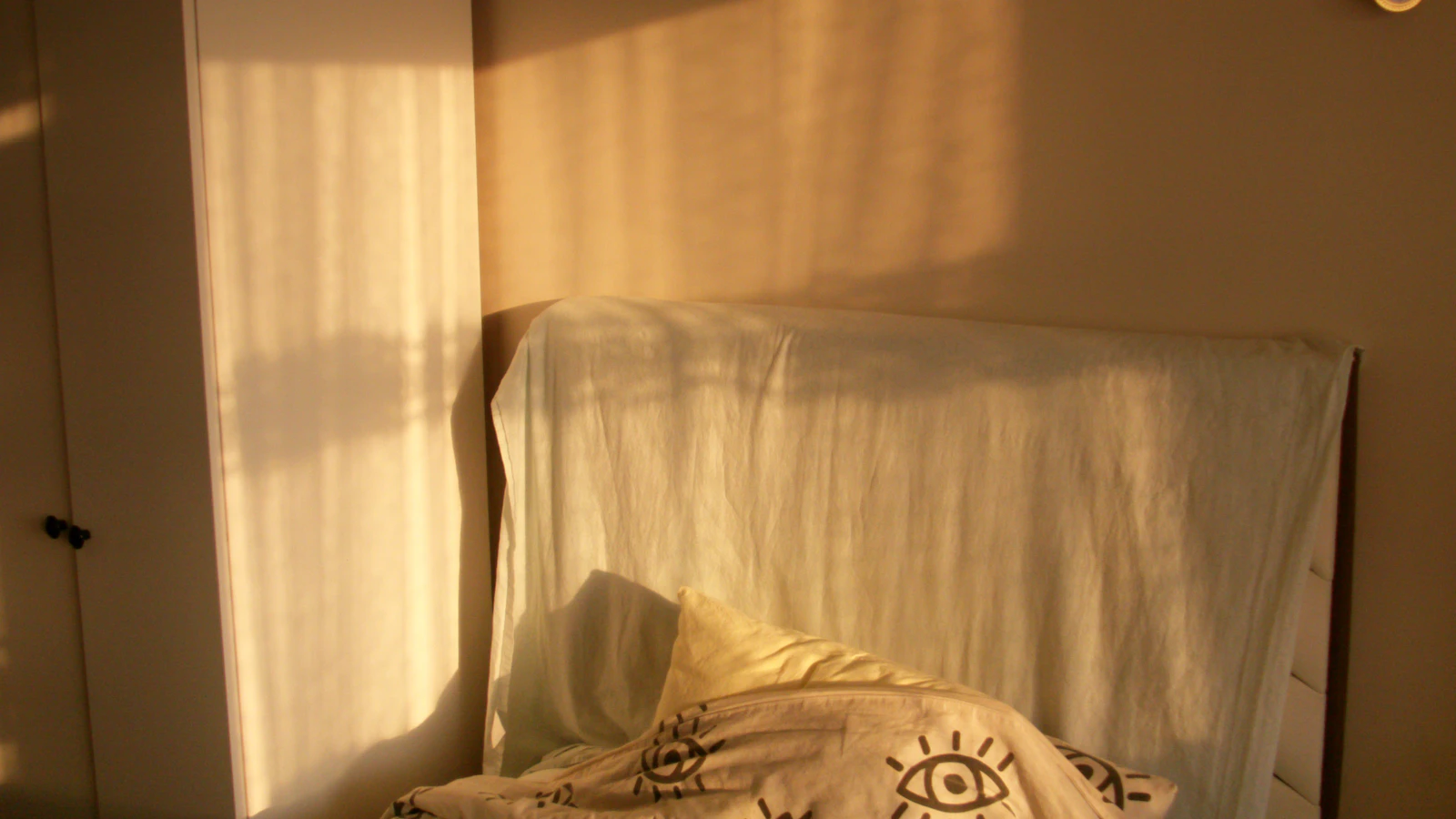 Onopgemaakt bed in een slaapkamer met ochtendlicht door het gordijn.